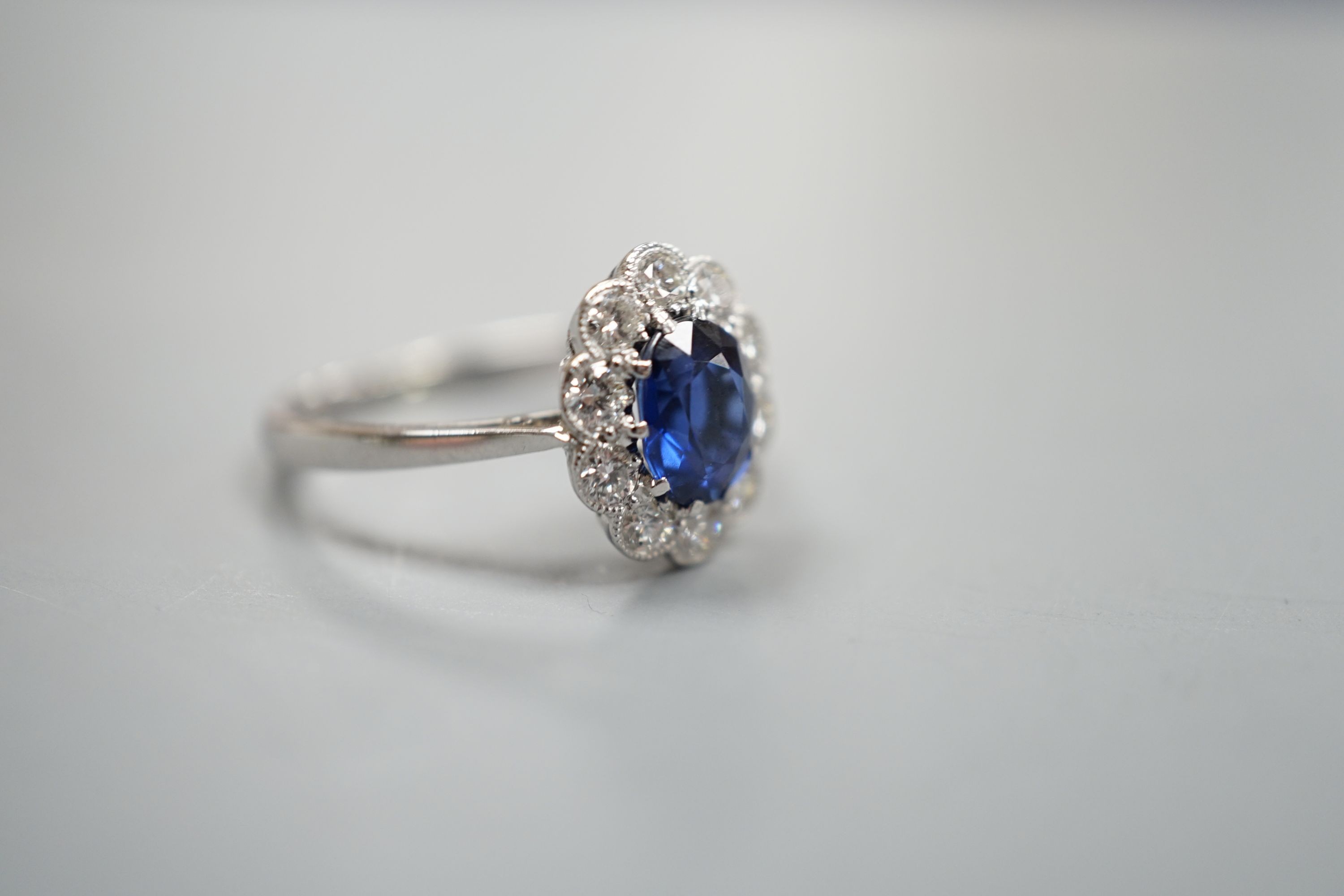 An 18ct and plat. sapphire and diamond set oval cluster ring, size N, gross weight 2.9 grams.